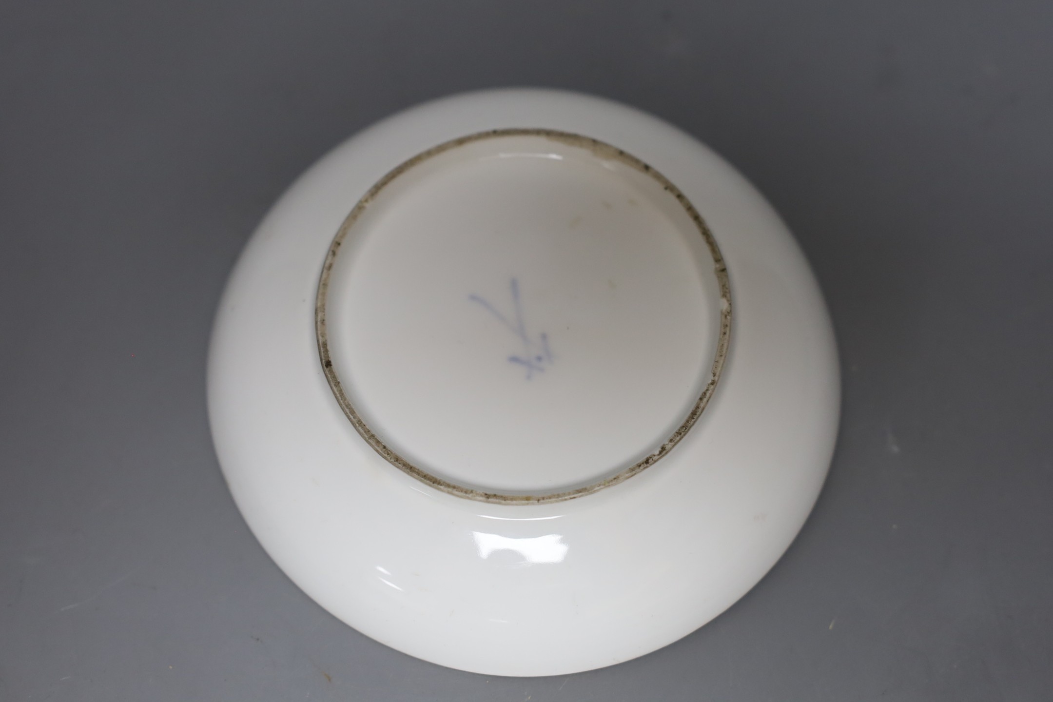 A Meissen teacup and saucer painted with a landscape with children in robes with recumbent sheep, crossed swords mark and dot in underglaze-blue, impressed numerals, saucer 13.5 cms diameter